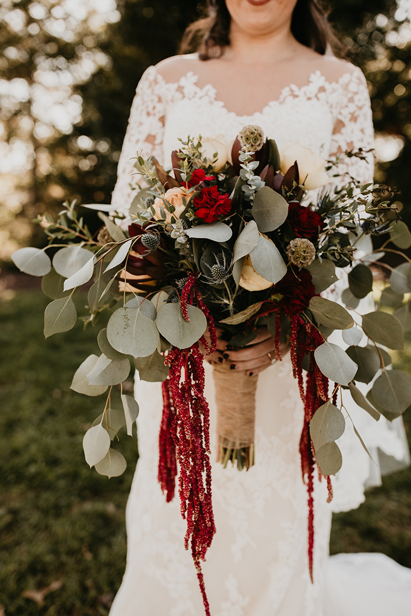 Bride holding burgundy flower bouquet
