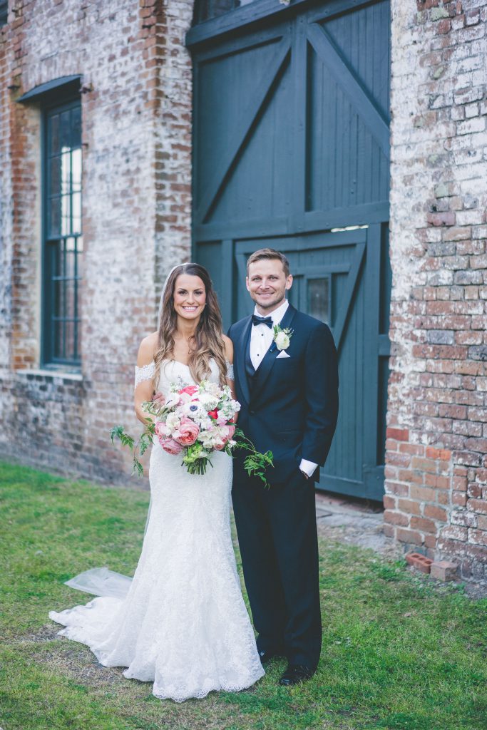 Bride and groom standing in front of brick building