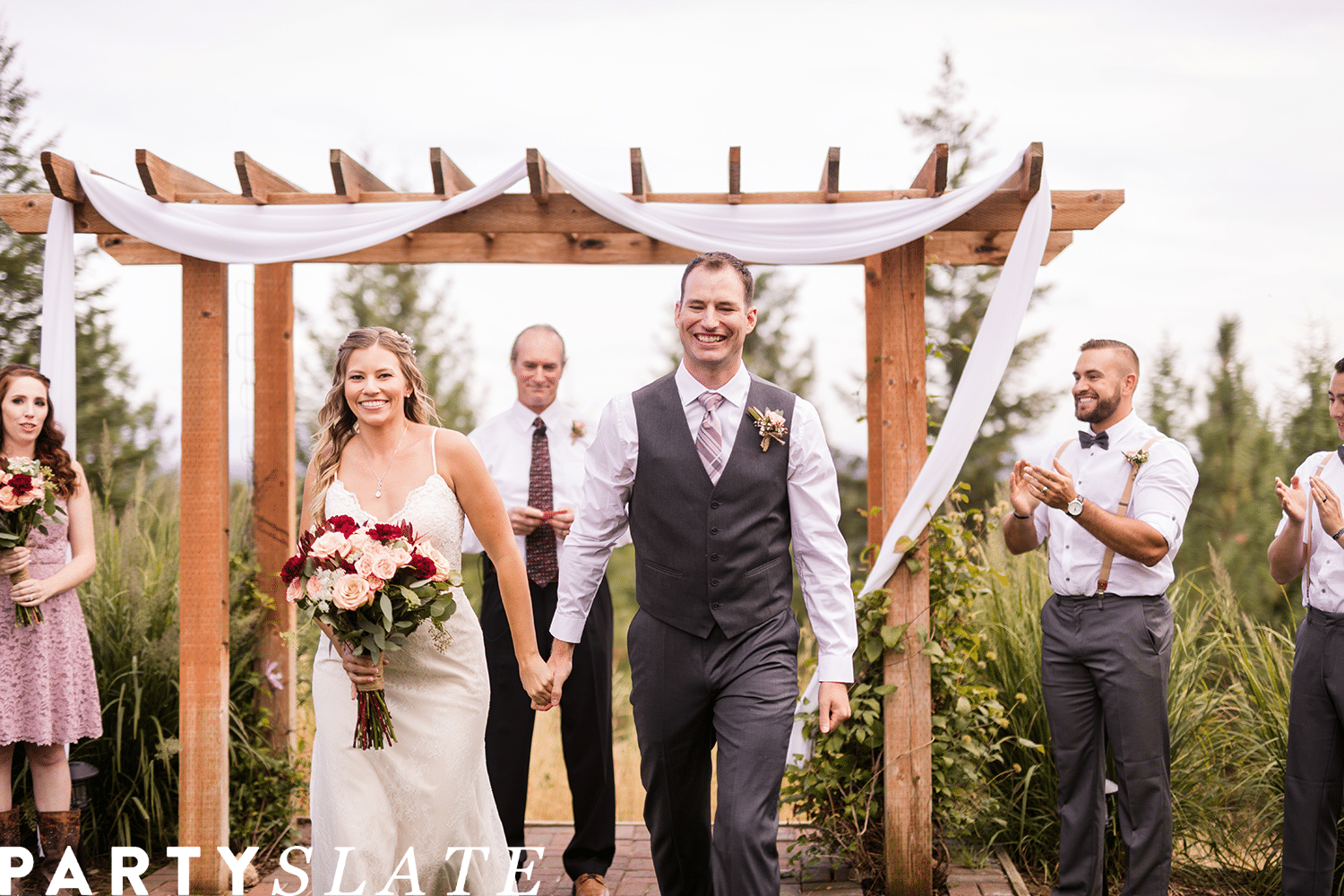 Bride and groom walking down the aisle with arbor in the background