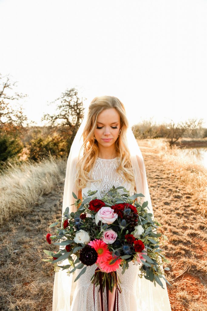 Bride with Rose, carnations, scabiosa, thistle, gerbera daisies, hypericum berries, and seeded eucalyptus bouquet