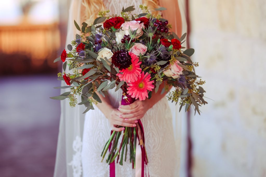 Rose, carnations, scabiosa, thistle, gerbera daisies, hypericum berries, and seeded eucalyptus bouquet