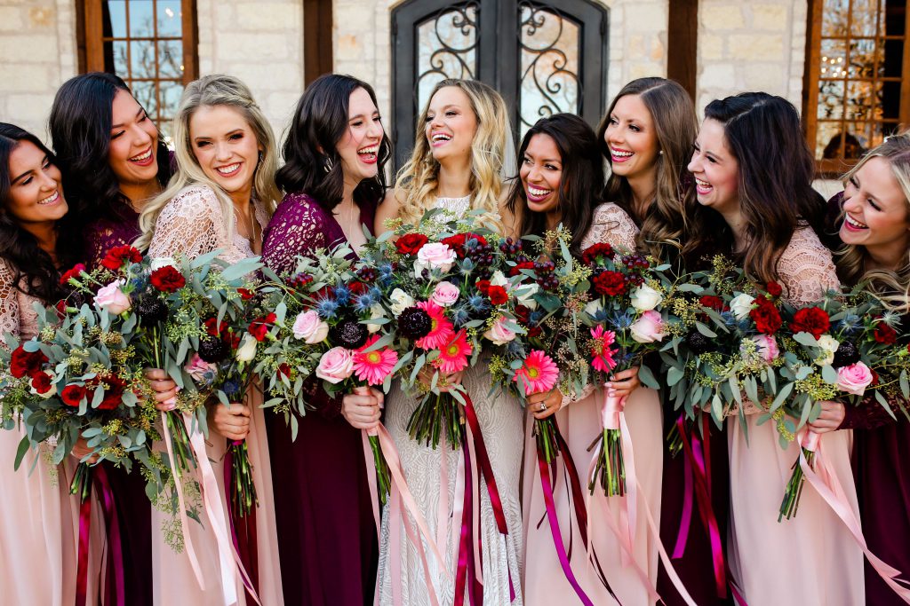 Bride and bridesmaid in white pink and purple dresses with flower bouquets