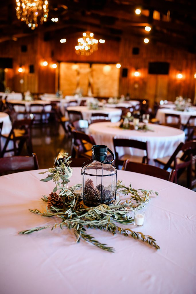 Centerpiece on a table with candles, a glass jar and a green stems for decoration