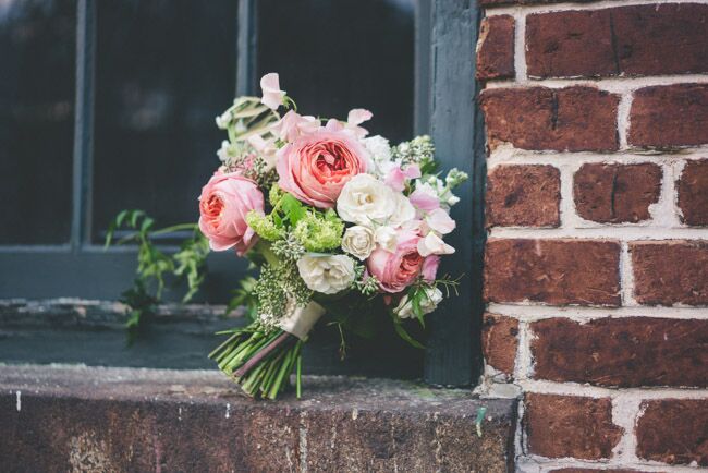 Pink and white DIY floral arrangement on a brick window sill