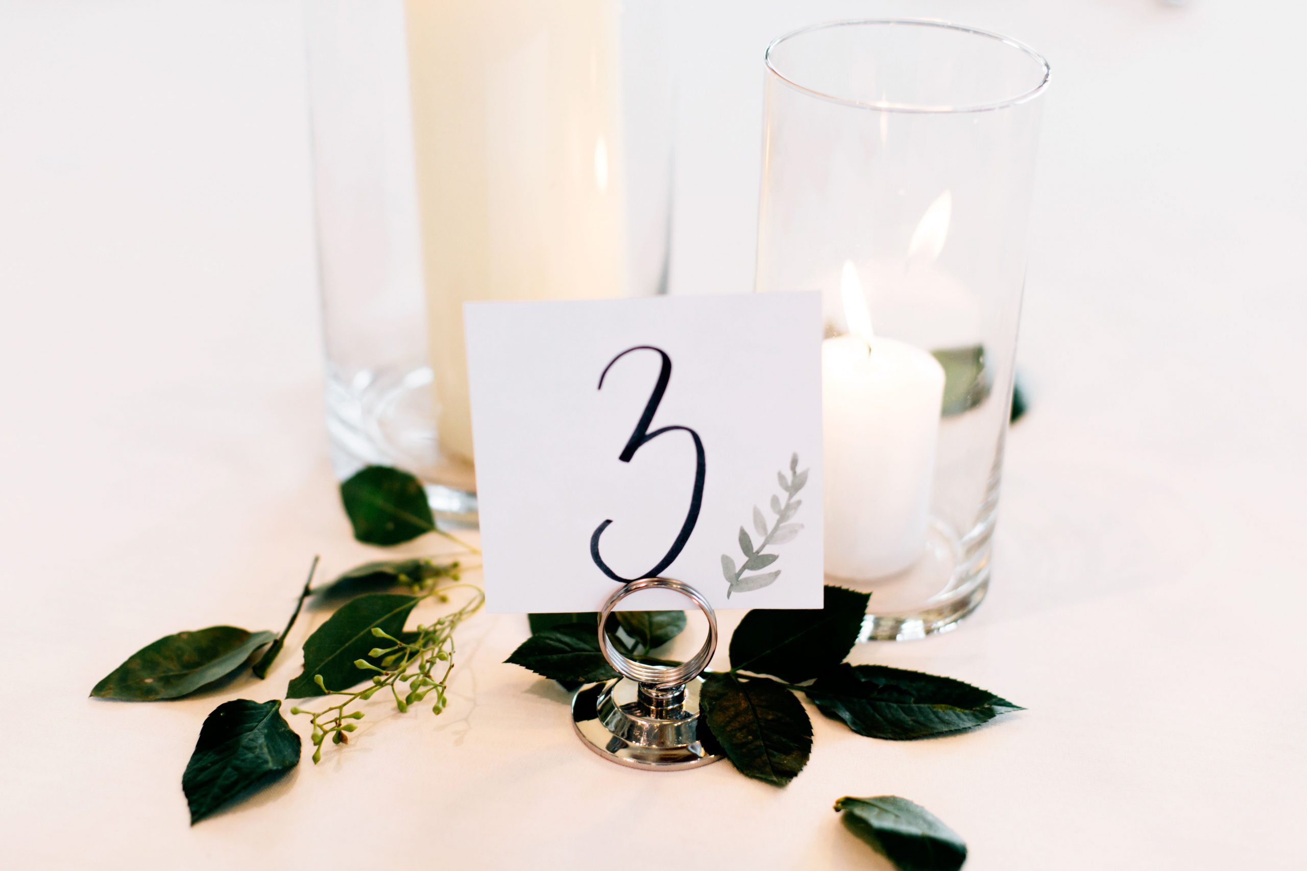 Candles and green leaves on a table with the number 3