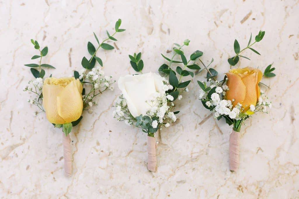 yellow rose with a sprig of Italian Ruscus greenery and baby’s breath for the groomsmen, and a white rose for the groom boutonnieres