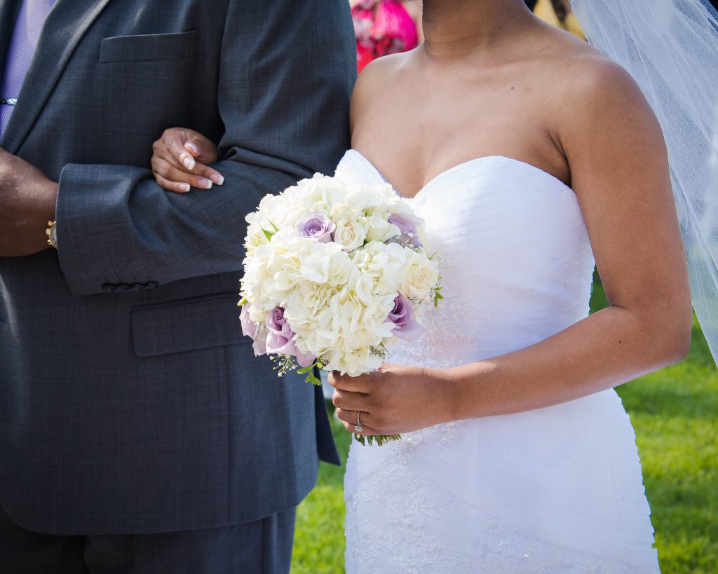 DIY with white hydrangeas, white roses, a few stems of baby’s’ breath, and a pop of color lavender roses bouquet with bride walking down the aisle