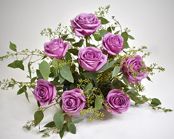 purple roses with seeded eucalyptus stems in floral foam