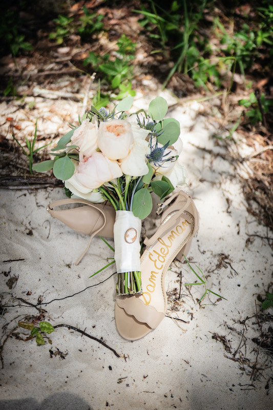 Photo of flower bouquet with shoes on a beach