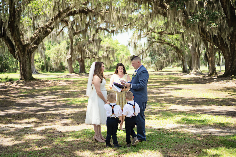 Wedding couple under large trees with two small children