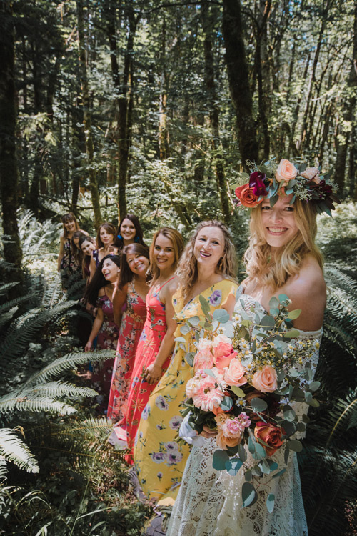 Women in tropical style dresses in the forest with bride wearing crown of flowers and holding a bouquet