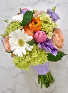 orange ranunculus, peach roses, green mini hydrangeas, white gerbera daisies, pink tulips, and lavender lisianthus