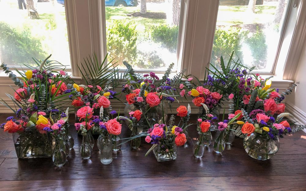 Multiple Table settings with various flowers in vases