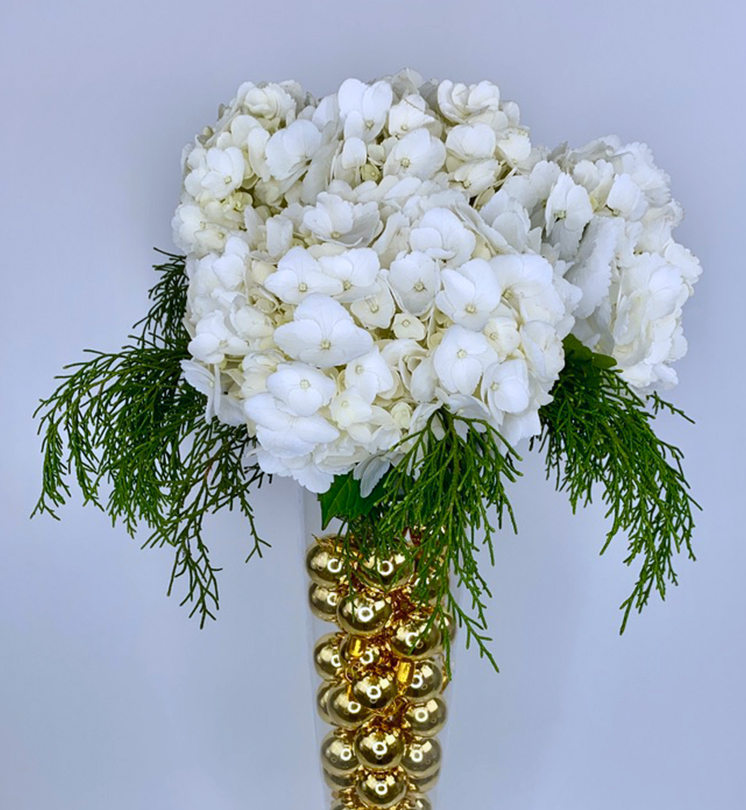 Glass with ornaments and white flowers in floral foam stacked on top