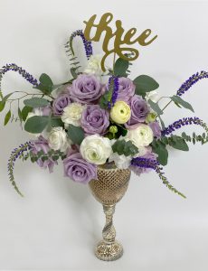 Tall centerpiece with purple and white flowers.