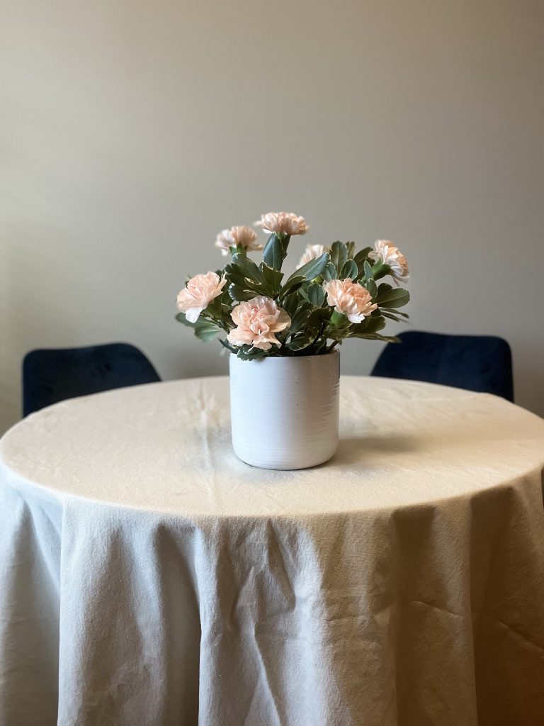 white vase with greens and peach carnations