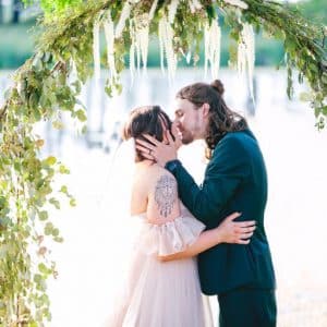 Bride & Groom Kissing Under Arbor