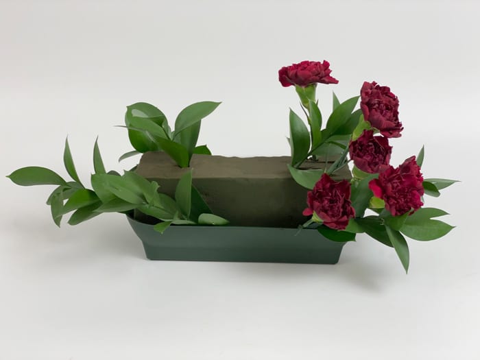 Adding Burgundy Carnations to Floral Foam