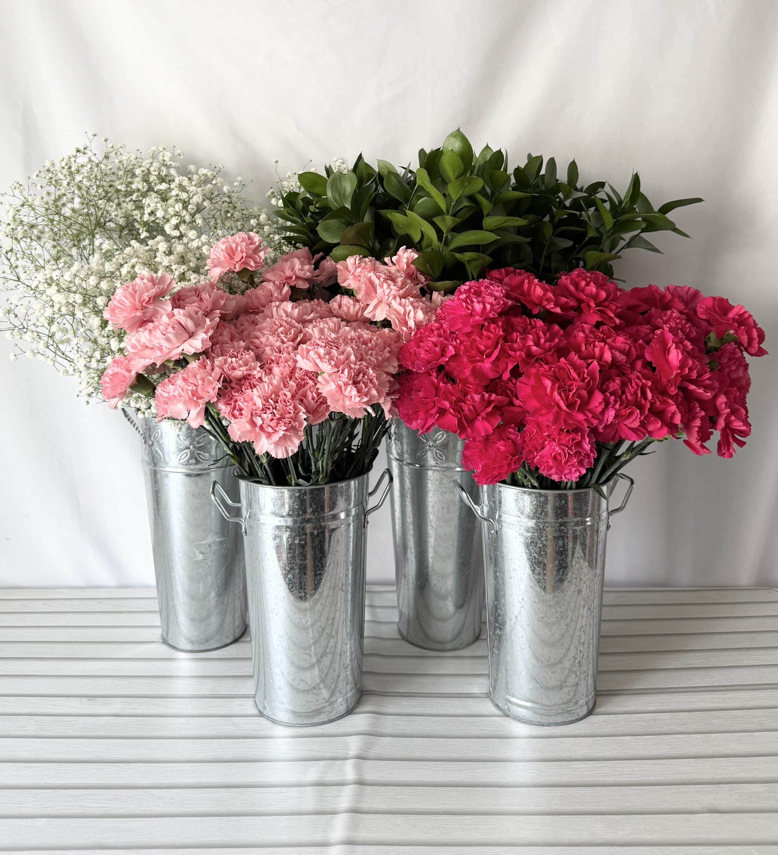 hot pink and light pink carnations in buckets with baby's breath and greenery