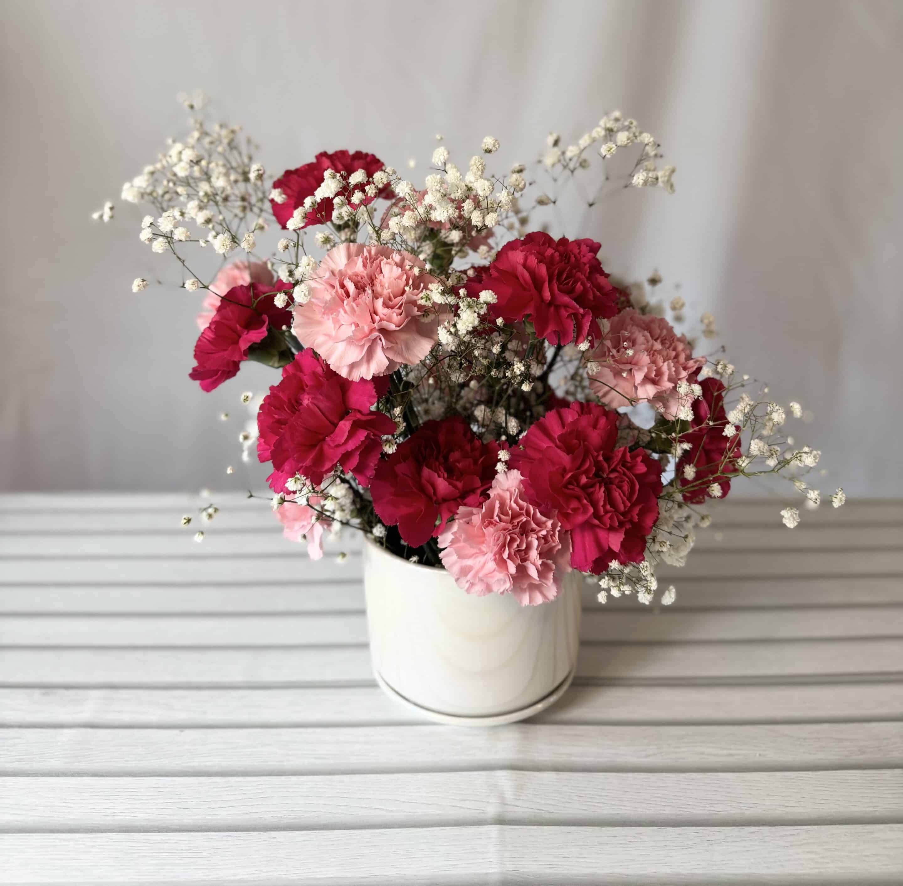 an arrangement of pink carnations with baby's breath