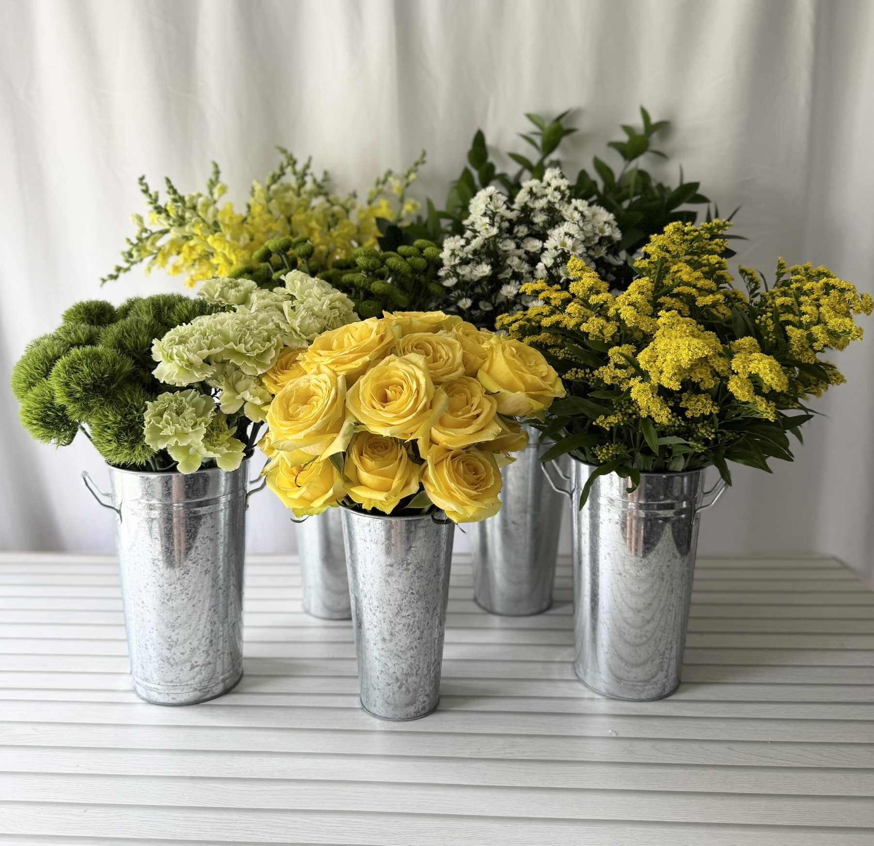 yellow and green flowers in galvanized buckets