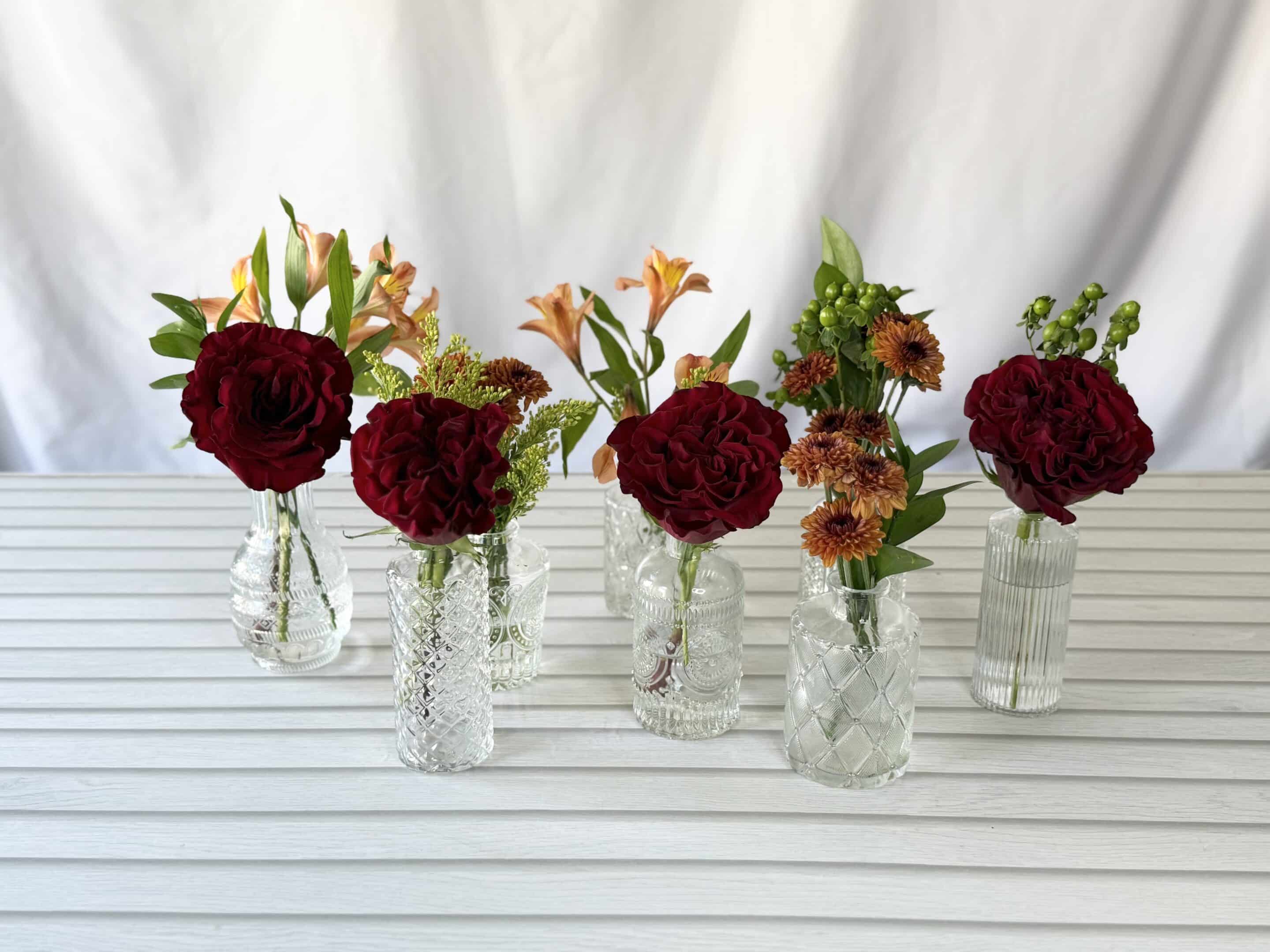 bud vases with varying fall colored flowers
